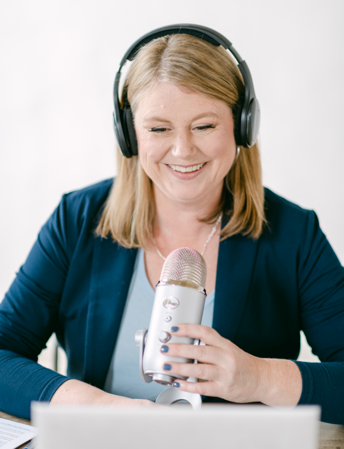 Heather Nelson in front of a podcast mic wearing headphones