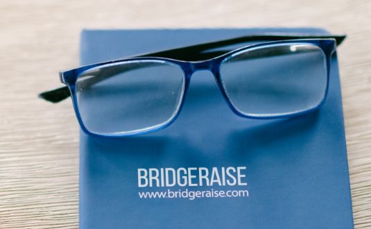 Eyeglasses placed on top of a Bridgeraise guidebook